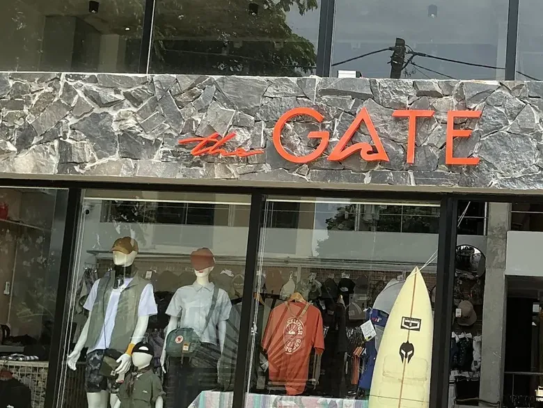 Mặt tiền cửa hàng The Gate Tam Cốc: biển hiệu chữ cam gắn trên tường đá, tủ kính bày quần áo và ma-nơ-canh.