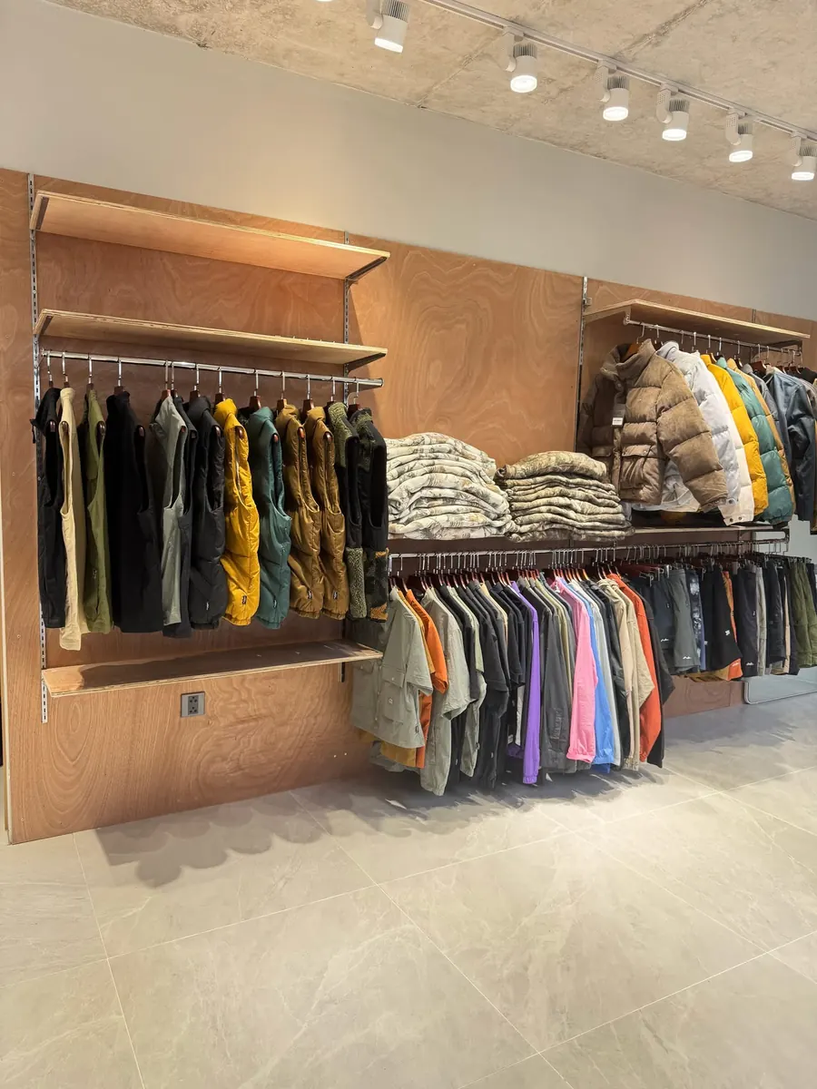 Vests and puffer jackets on the plywood wall display