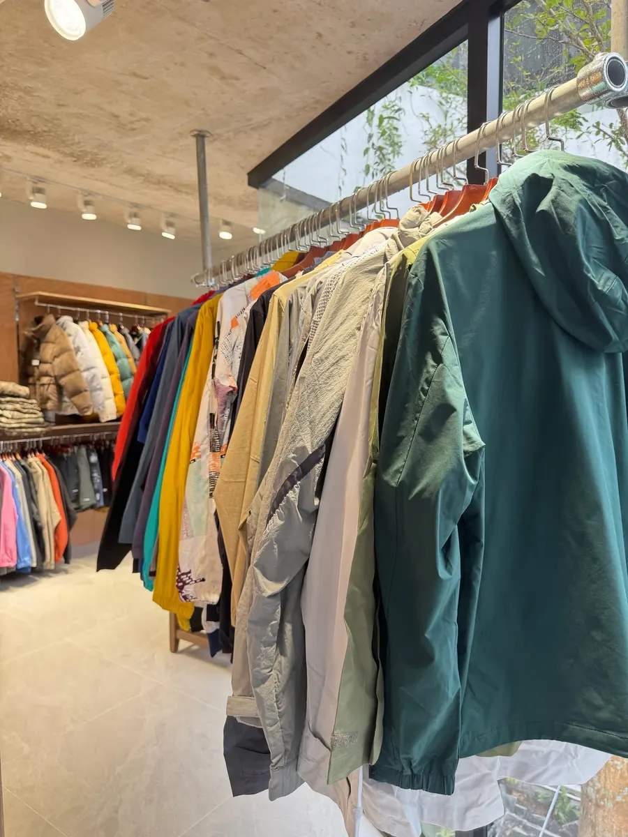 Windbreakers and light jackets on a rack by the window